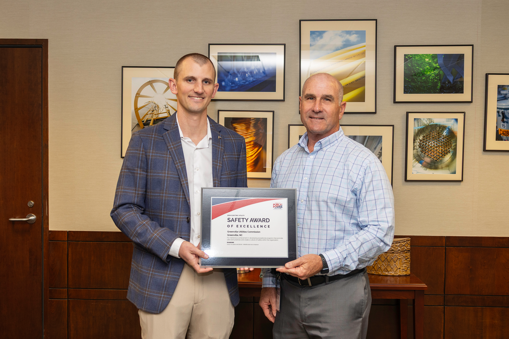 Two men hold award